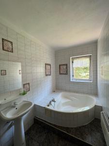 un bagno bianco con vasca e lavandino di Dedinky Lakeview Cottage a Dedinky