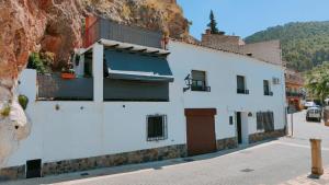 a white building on a street next to a mountain at Alojamiento Rural El Peñon de Hornos in Hornos