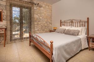 a bedroom with a bed and a stone wall at Kymaros Villas in Keri