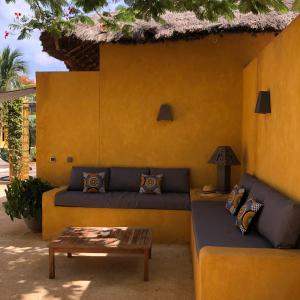 a couch sitting in front of a yellow wall at Toubana Lodge in Ngaparou
