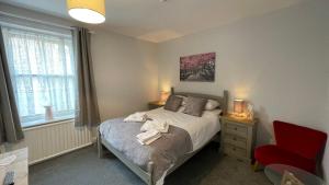a bedroom with a bed and a red chair at Anglebury House in Wareham