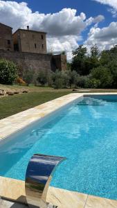uma grande piscina azul em frente a um castelo em Borgo Loretello em Loretello