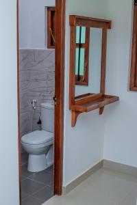 a bathroom with a toilet and a mirror at UD Garden Hotel in Kataragama