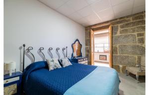 a bedroom with a blue bed and a stone wall at Beautiful Apartment In A Arnoia in Arnoia