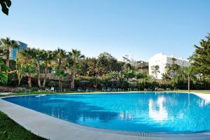 una gran piscina azul con sillas y árboles en Apartamento Costa Zahara, en Zahara de los Atunes