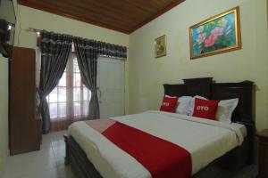 a bedroom with a bed with red pillows and a window at Penginapan Bunga Sonsang Padang Syariah in Tabing