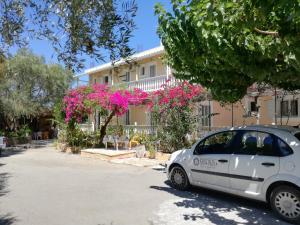 ein weißes Auto, das vor einem Haus mit rosa Blumen parkt in der Unterkunft Casa Dyonisia Tsilivi in Planos