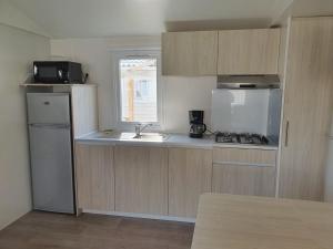 eine kleine Küche mit Spüle und Kühlschrank in der Unterkunft Mobil home - Clim, TV - Camping '4 étoiles' - Narbonne Plage - 014 in Narbonne-Plage