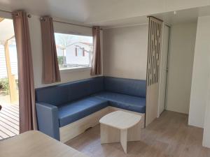 a blue bench in a room with a window at Mobil home - Clim, TV - Camping '4 étoiles' - Narbonne Plage - 014 in Narbonne-Plage