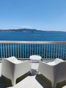 2 weiße Stühle und ein Tisch auf dem Balkon mit Blick auf das Wasser in der Unterkunft Magnifique duplex vue mer inoubliable Sanary Sur Mer in Sanary-sur-Mer