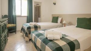 een slaapkamer met 2 bedden en groene en witte dekens bij Villa Aldeia do Golf - BY BEDZY in Vilamoura