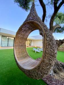 a rattan swing hanging from a tree in a yard at VISTA LAGO VILLE in Chiclana de la Frontera