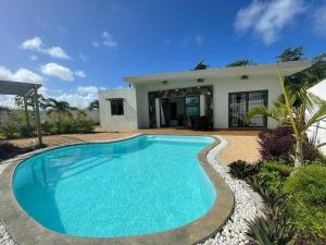 a swimming pool in front of a house at Villa des palmiers in Grand-Baie