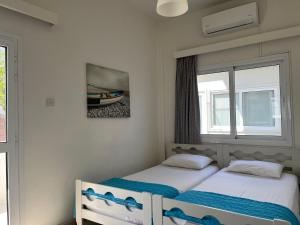 Dos camas en una habitación con dos ventanas. en Themis Beach Apartments, en Lárnaca