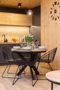 a dining room with a table and chairs and a clock at Luxury Salwatoriańska Apartments Mountain View Zakopane by Renters Prestige in Zakopane