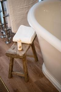 a stool next to a bath tub next to a toilet at The Cotley Inn in Wambrook