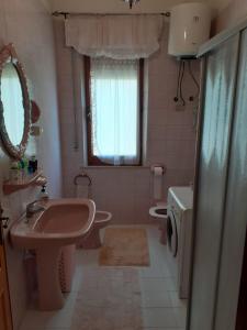 een badkamer met een wastafel, een toilet en een spiegel bij B&B ANNA in Piscinas