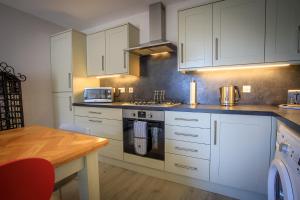 a kitchen with white cabinets and a wooden table at Cosy Cottage in Fishertown, Nairn - Free Parking & Pets welcome! in Nairn