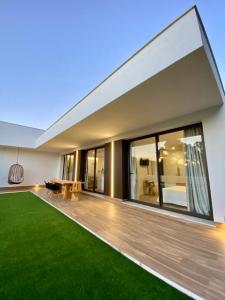 a large house with a large deck with green grass at VISTA LAGO VILLE in Chiclana de la Frontera