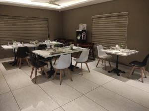 uma sala de jantar com mesas e cadeiras brancas em Soorya em Attingal