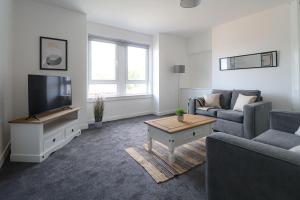 a living room with a couch and a tv at The Cove Apartment in Gourock