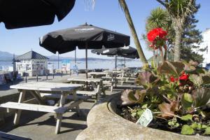 uma fila de mesas de piquenique e guarda-sóis numa praia em The Bulkeley Hotel em Beaumaris