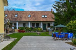 a house with a table and chairs in the yard at Falubíró Vendégháza in Bekölce