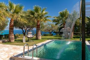 a swimming pool with palm trees and a fountain at Kymaros Villas in Keri