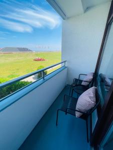 a balcony with two chairs and a view of a field at Apartment Seesrauschen für 2-4 Personen mit Pool in Dahme