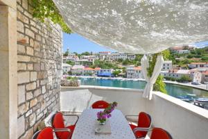 a table and chairs on a balcony with a view of the water at Villa Povlja in Povlja