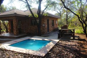 a brick house with a swimming pool and a picnic table at Nature Cottage in Marloth Park