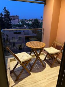 d'une table en bois et de deux chaises sur un balcon. dans l'établissement Superbe appartement à l Hivernage, à Marrakech