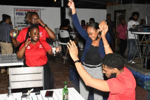 Un groupe de personnes assises à une table avec les mains en l'air dans l'établissement Metro Hotel Couva, à Couva