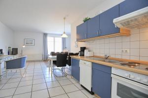a kitchen with blue cabinets and a dining room at Dünenblick Wohnung 50 in Boltenhagen