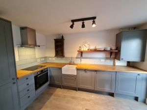 a large kitchen with blue cabinets and a sink at The Little Cottage - Peaceful, Dog Friendly Cottage in 5 Acres in Glastonbury