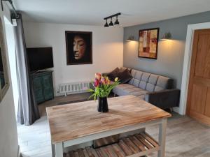 a living room with a couch and a table with flowers at The Little Cottage - Peaceful, Dog Friendly Cottage in 5 Acres in Glastonbury