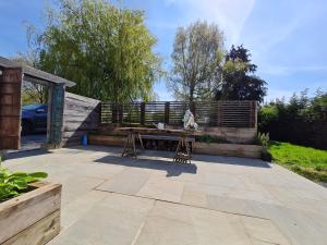 a patio with a wooden bench and a table at The Little Cottage - Peaceful, Dog Friendly Cottage in 5 Acres in Glastonbury