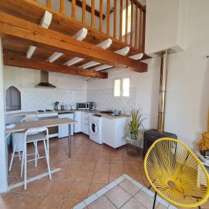 une cuisine avec une table et une chaise jaune dans l'établissement Le gîte de La Badassière, à Forcalquier