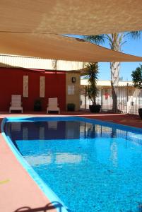 uma piscina com um guarda-chuva sobre ela em Desert Sand Motor Inn em Broken Hill