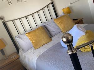 a bed with yellow and white pillows on it at Meadowview Cottage, Garden View in Camborne