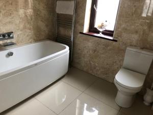 a bathroom with a tub and a toilet and a window at Meadowview Cottage, Garden View in Camborne