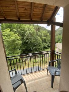 d'un balcon avec deux chaises et une vue sur les arbres. dans l'établissement Hotel de la Jonte, à Meyrueis