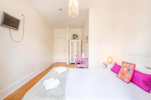 a white bedroom with a large bed with purple pillows at Happy at Chiado in Lisbon