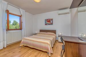a bedroom with a bed and a desk and a window at La Quiete B&B in Lovrečica
