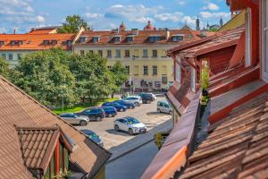 Grotthuss Boutique Hotel — View over a red-tiled roofs to a tree-lined square with parked cars and yellow buildings with blue-framed windows