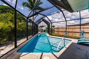 una piscina cubierta con una casa de cristal en NEW! Dock Canal Family Home w/Pool & Gulf Access!, en North Fort Myers