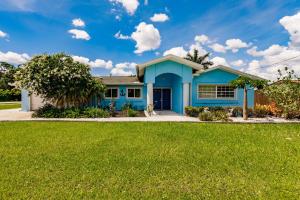 una casa azul con césped verde en NEW! Dock Canal Family Home w/Pool & Gulf Access! en North Fort Myers