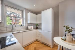 a kitchen with white cabinets and a table and a window at Superb 2 bed apartment near Camden Town FREE WIFI in London