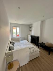 a white bedroom with a bed and a chair at Appartement Centre ville Le Havre in Le Havre