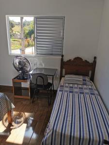 a bedroom with a bed and a desk and a window at Casa do Diogo in Capitólio